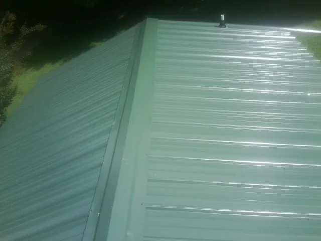 New green metal panels meeting at the ridge of a roof — Flat Roof Repair work by our crew in Winnemucca