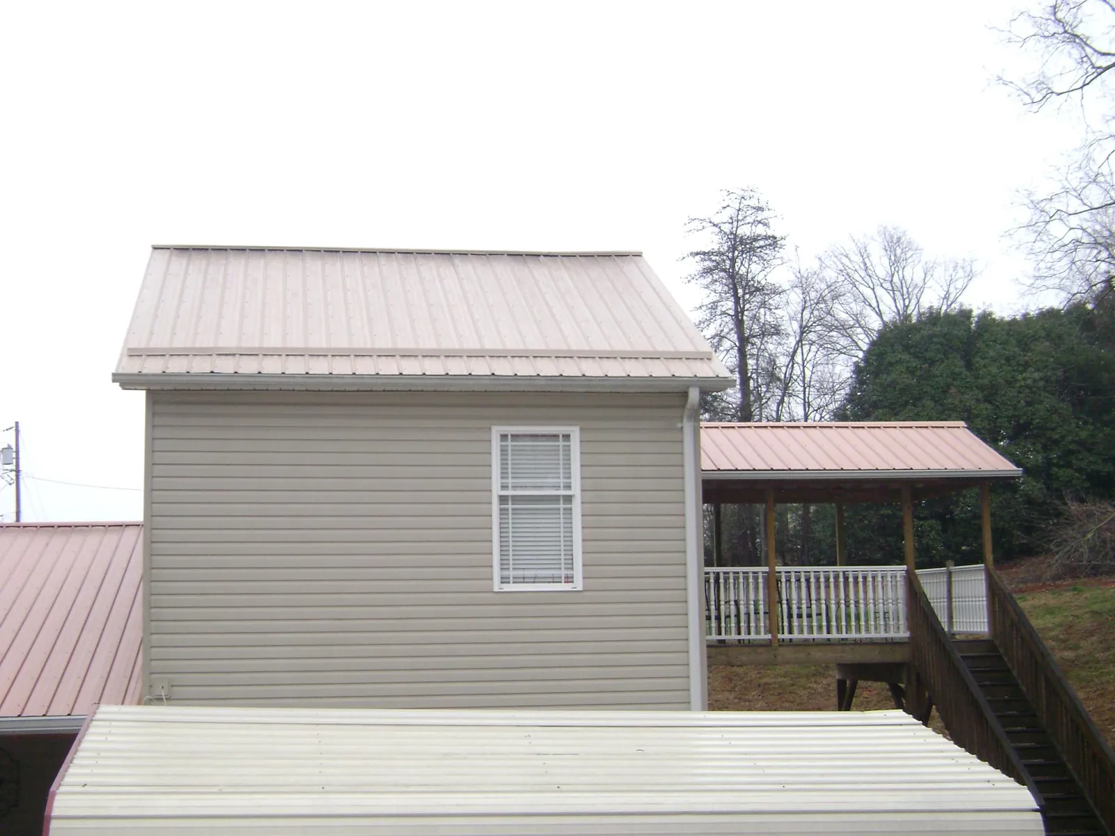 Tan metal roofs on a two story addition and attached porch, from a Roof Replacement job in Winnemucca